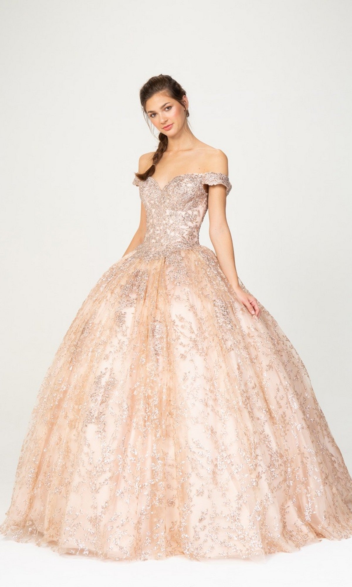A woman stands against a plain light background wearing the Eureka 9909 long prom dress in rose gold, featuring lace off-the-shoulder style and sparkling sequin embellishments.